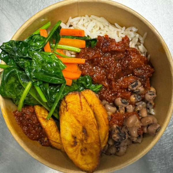 A plate of rice and beans served with fried plantain, tomato stew, and spinach vegetable garnish.